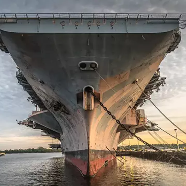 The hull of an aircraft carrier anchored in a shipyard